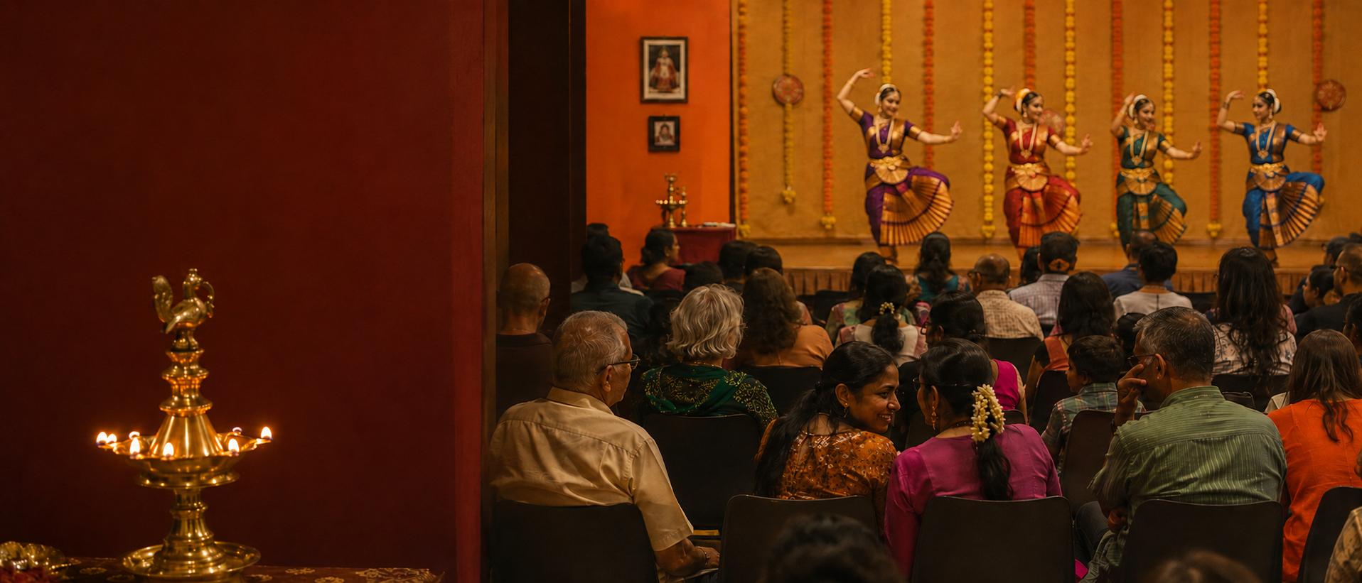Events — Community hall during a festival evening: rows of people facing a stage, brass oil lamp in the foreground, marigold garlands, multi-generational Singaporean audience