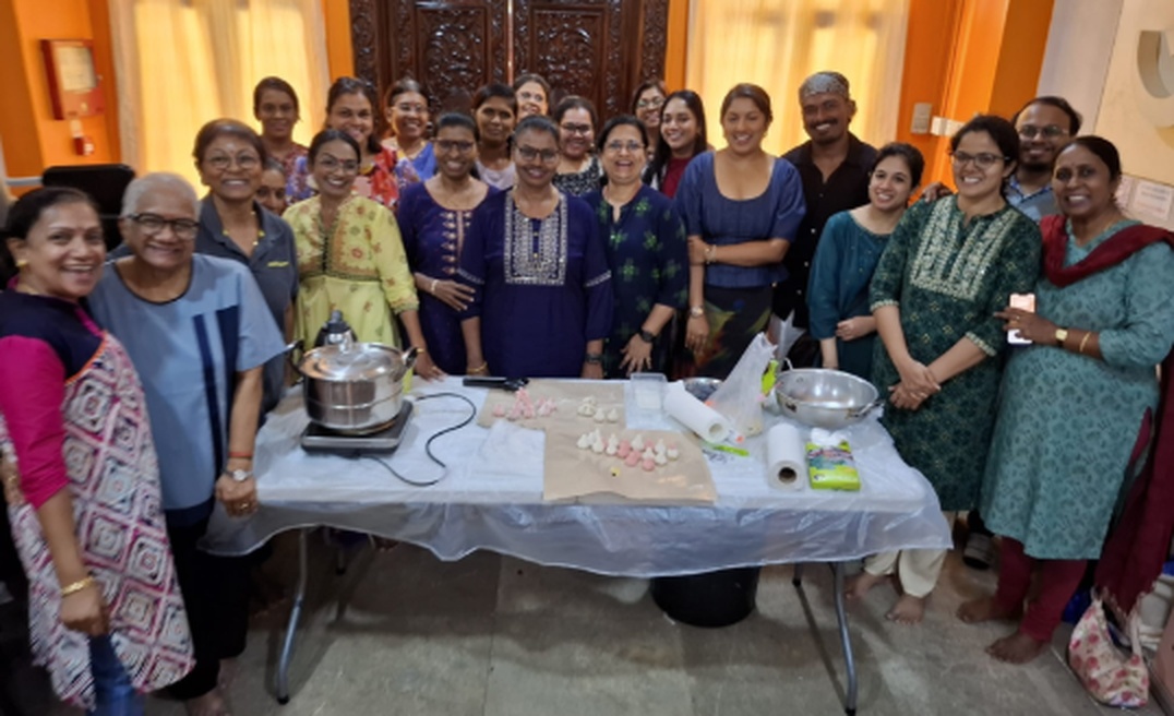 Group portrait at a Naivedyam-making (fusion modhakam) workshop at Hindu Centre, table laid with prepared offerings in the foreground