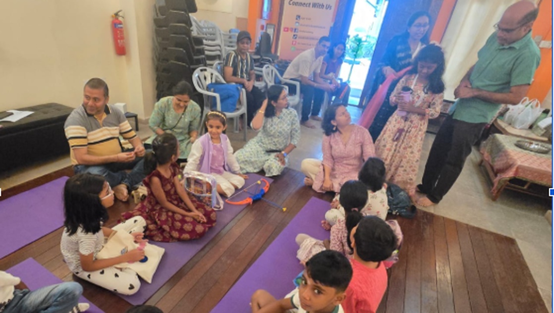 Children and parents on yoga mats during an interactive Balagurukulam activity with traditional storytelling props