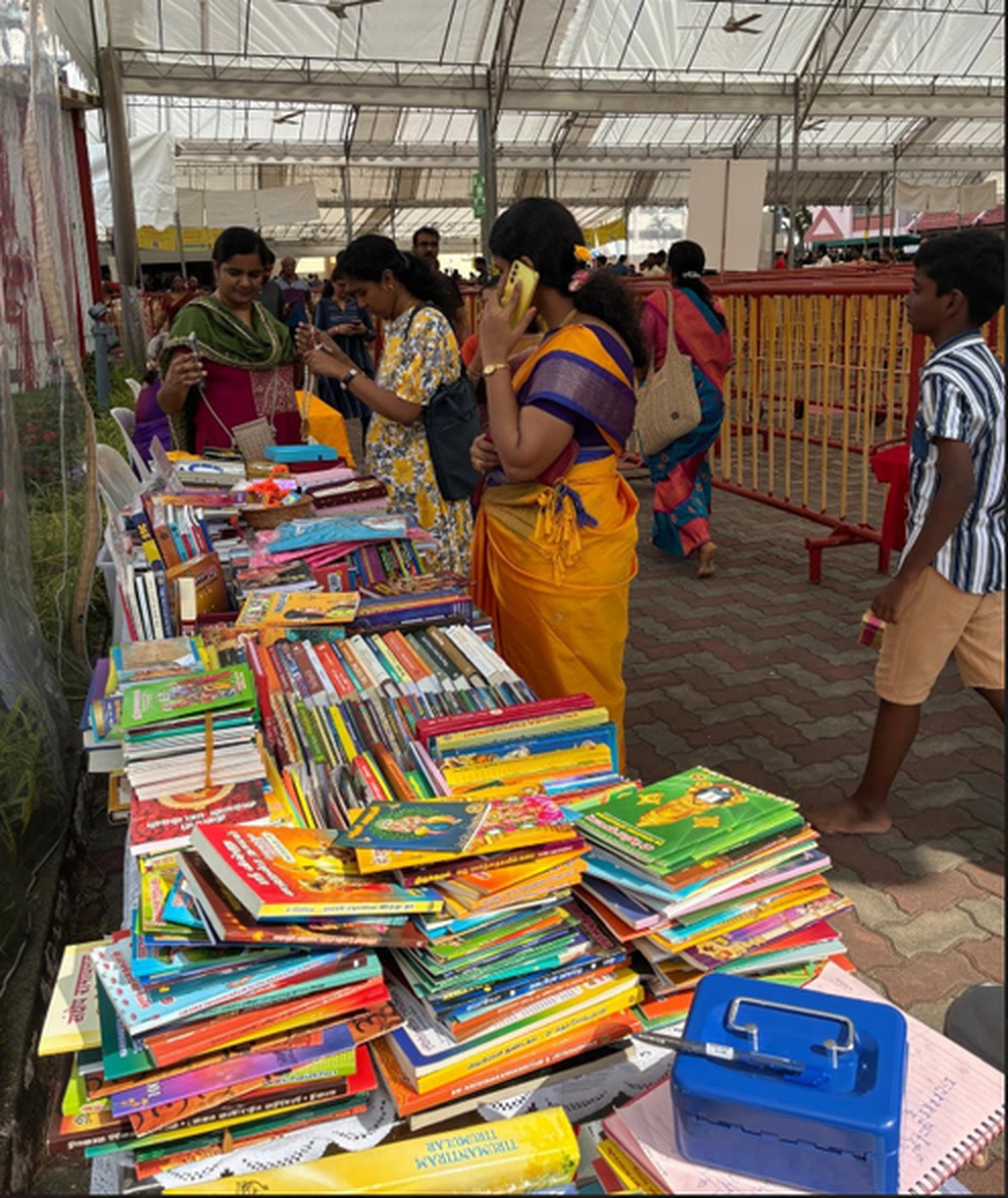 Hindu Centre book sales stall at a Singapore festive mela — visitors browsing tables stacked with children's books and Hindu texts under a covered tent